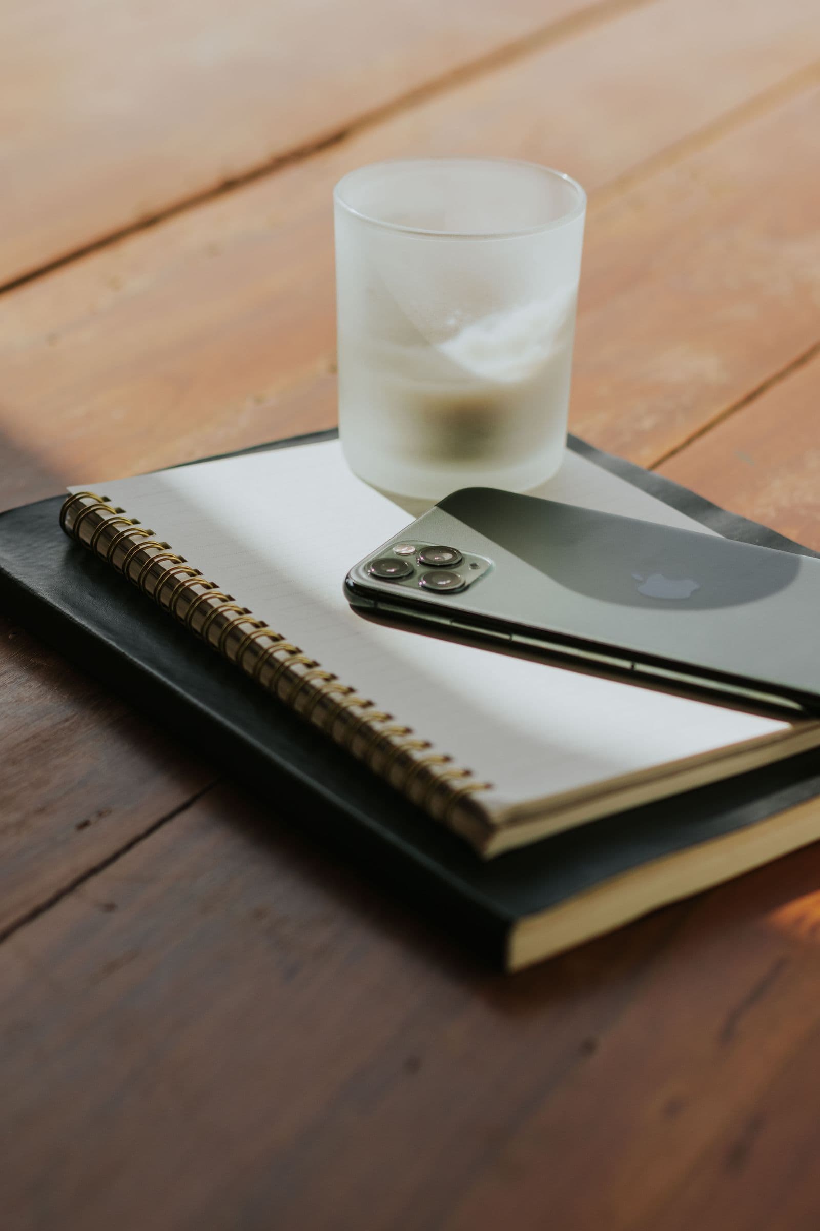 Carnet, téléphone et bougie posés sur un bureau en bois clair, ambiance calme d'écoute et de prise de notes