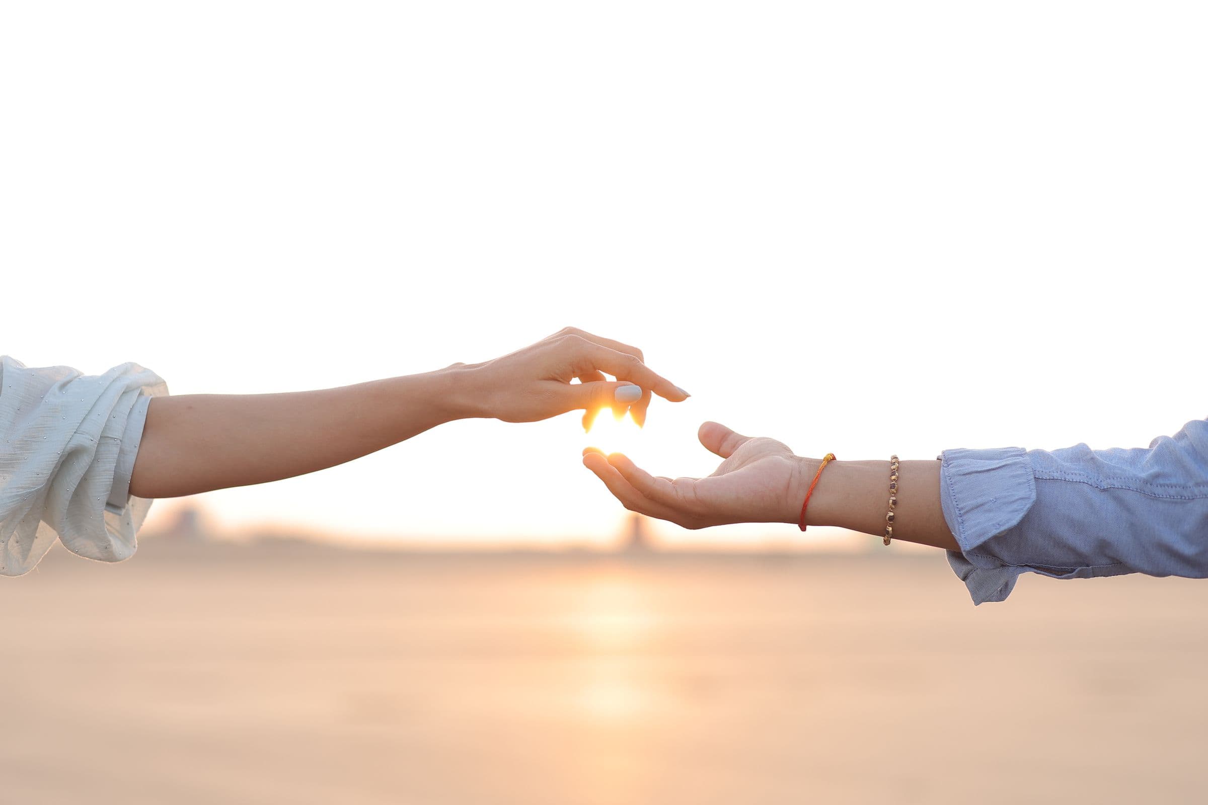 Deux mains qui se rejoignent dans une lumière chaude de coucher de soleil, symbole de reconnexion